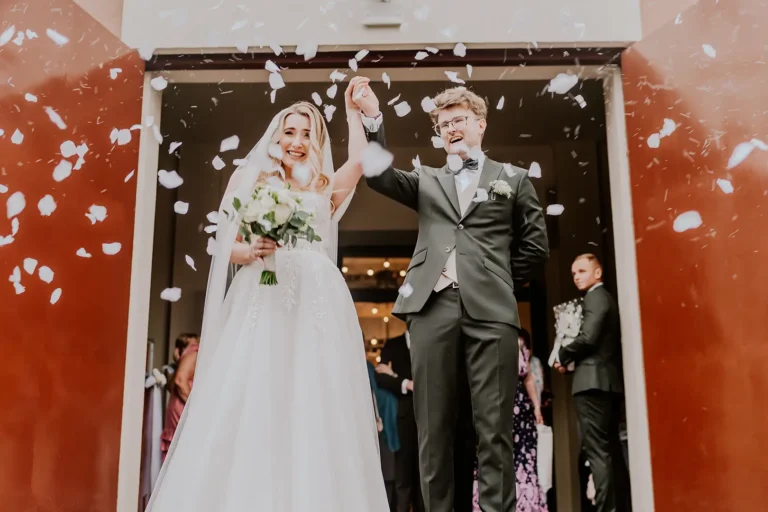 Para młoda wychodzi z kościoła obsypywana płatkami kwiatów – fotografia ślubna Łódź