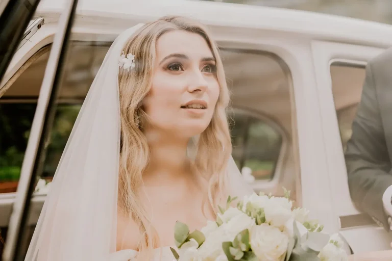Panna młoda w welonie i z bukietem obok samochodu ślubnego – fotografia ślubna Łódź