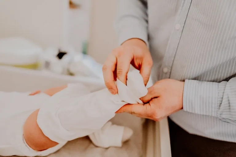 Ubieranie niemowlęcia w białe ubranko do chrztu