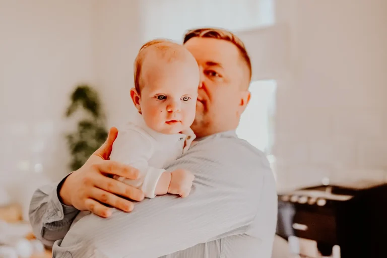 Ojciec trzyma dziecko podczas przygotowań do Chrztu Świętego