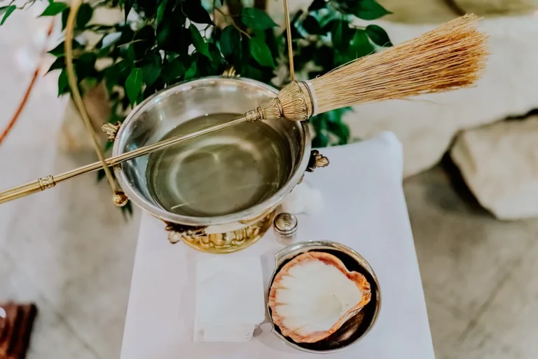 Woda święcona i kropidło przygotowane do Chrztu Świętego w kościele