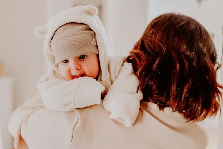 Niemowlę w białym ubranku i czapce podczas przygotowań do chrztu