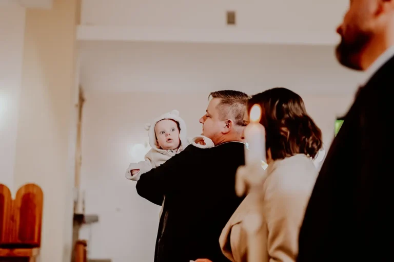 Ojciec trzyma dziecko w kościele podczas Chrztu Świętego